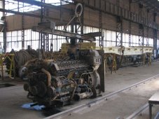 Moteur diesel en réparation. À l'arrière on voit un wagon du train chinois, en réparation dans cet atelier.